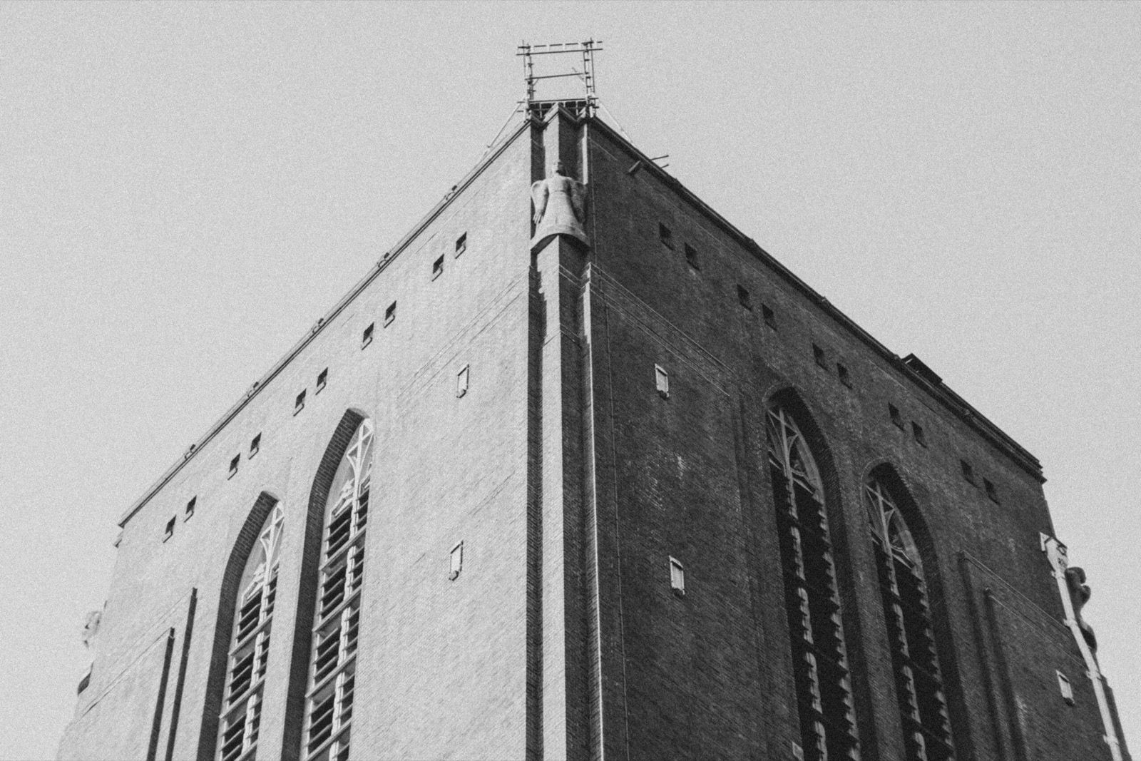 Black and white low-angle photograph of a brick tower against an open sky
